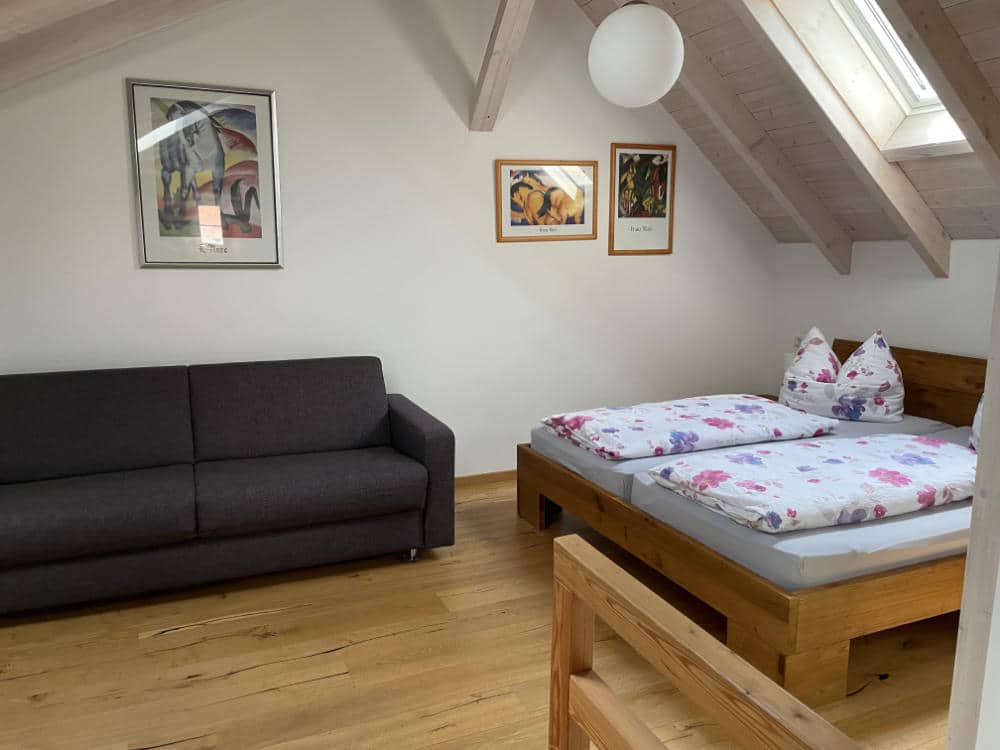 Das Doppelbett und das Sofa im offenen Schlafzimmer im OG des Ferienhauses