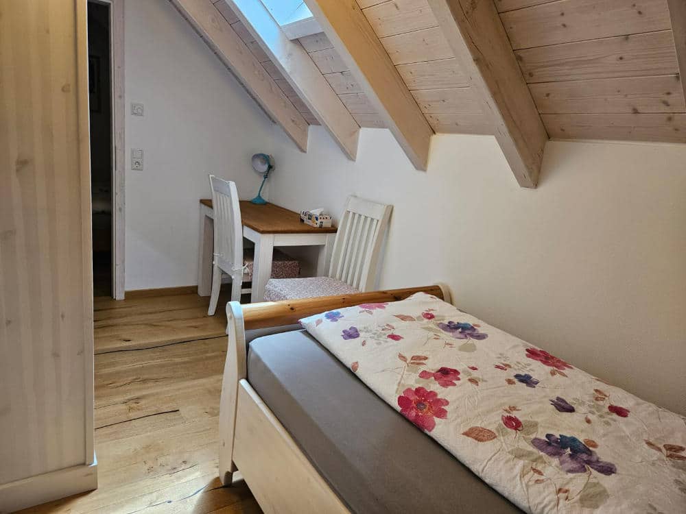Das Einzelschlafzimmer im OG mit Einzelbett und Tisch.